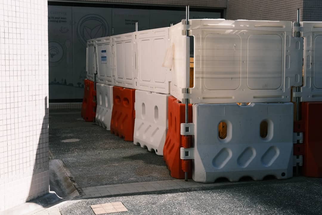 Plastic roadblock barriers with red and white colors in an urban area.