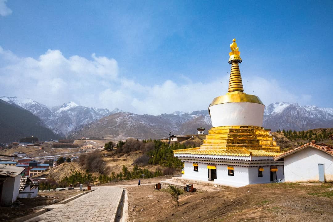 A Buddhist stupa in a Tibetan border town below snow peaks