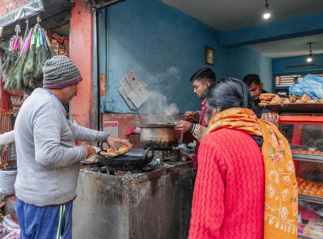 People cooking and serving food at a bustling street food stall in Kathmandu, Nepal.