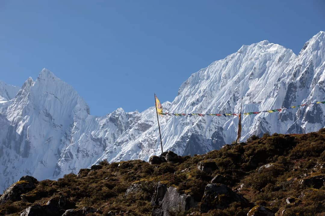 Snow-covered peaks and prayer flags in Thoche, Nepal, capturing breathtaking Himalayan beauty.