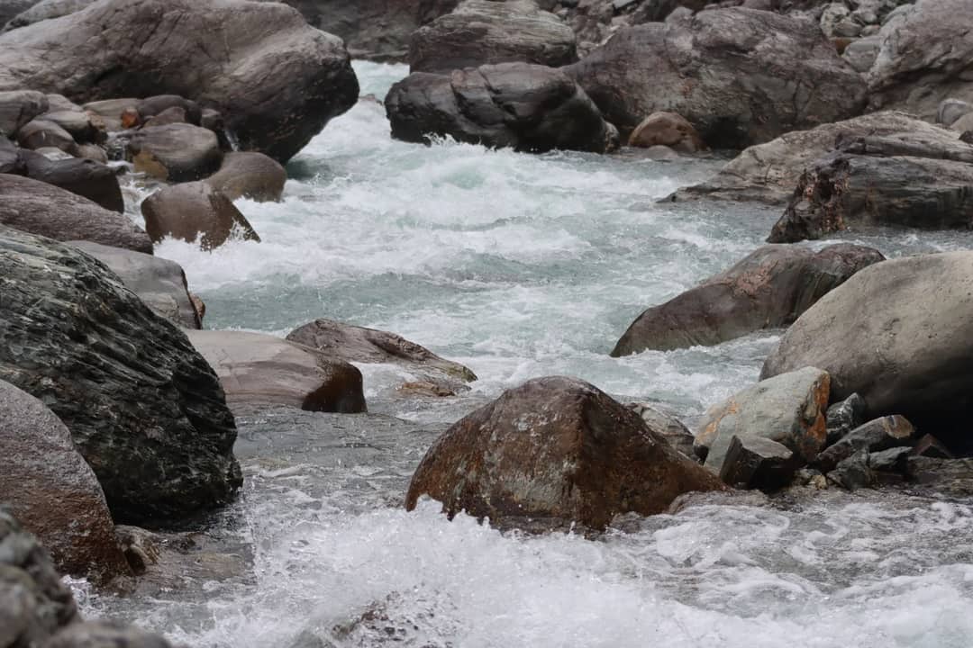 Eroded rocks and flowing stream in Tatopani, Nepal, showcasing nature's raw beauty.