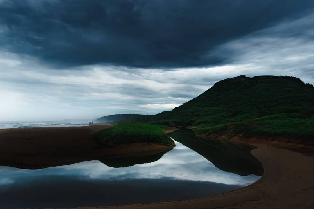 A scenic view of a stormy sky over a serene coastline in Visakhapatnam, India.