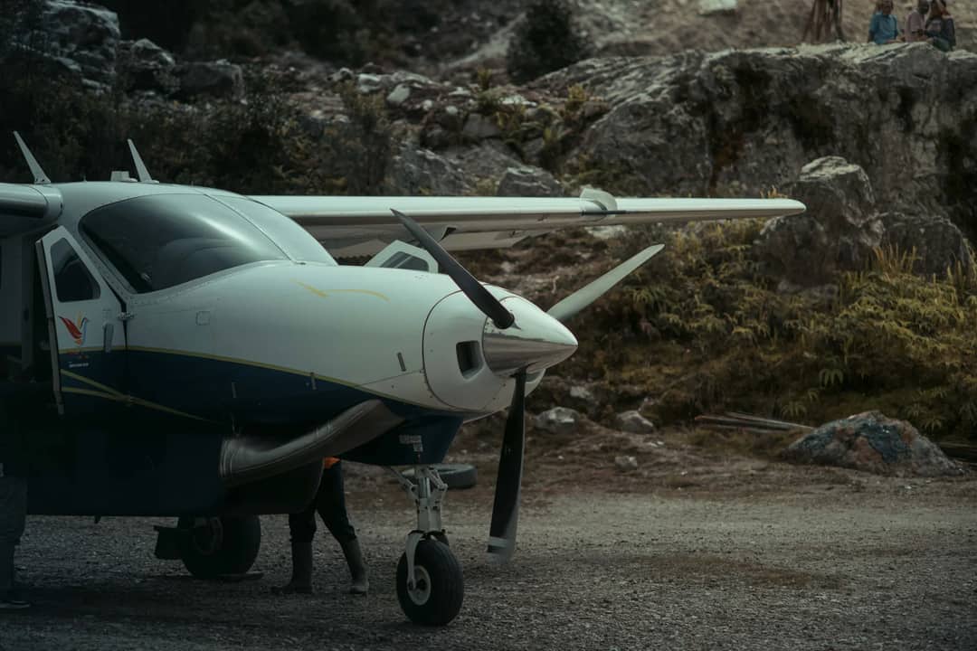 A small aircraft is parked in a rugged outdoor setting, showcasing its robust wings and propeller.