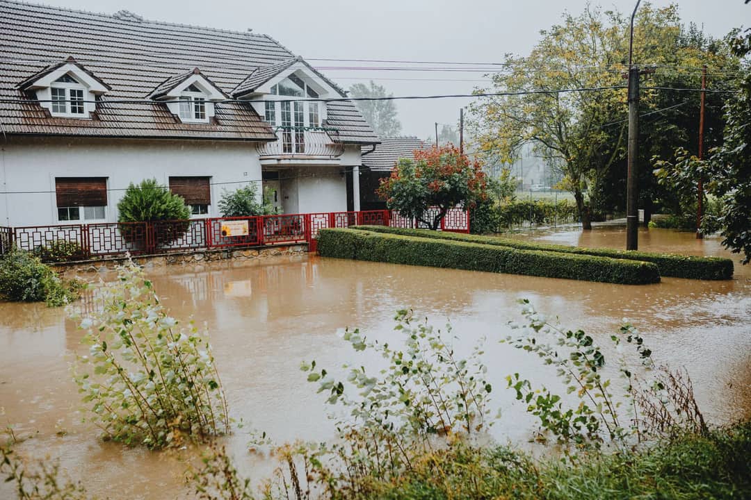 A suburban house surrounded by floodwaters after heavy rain, showing impact of natural disaster.