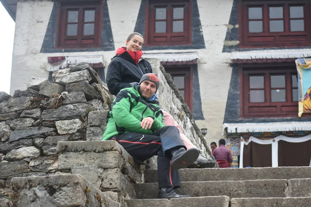 a man and woman sitting on a stone wall