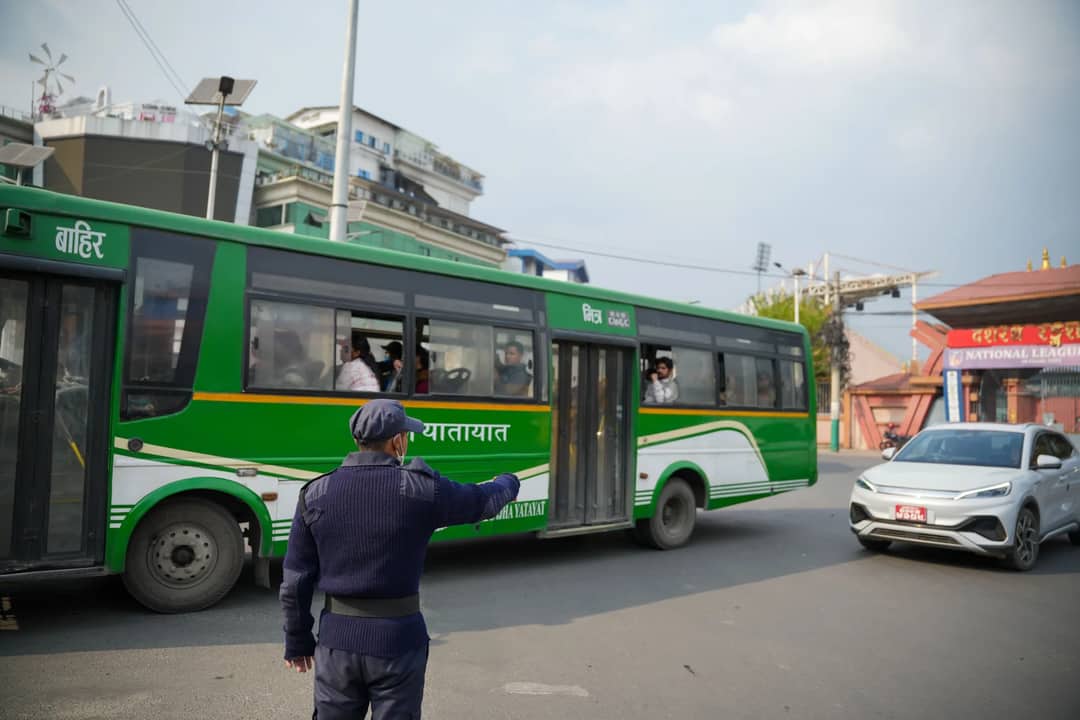 Policeman directing traffic in bustling Kathmandu street with bus and car.