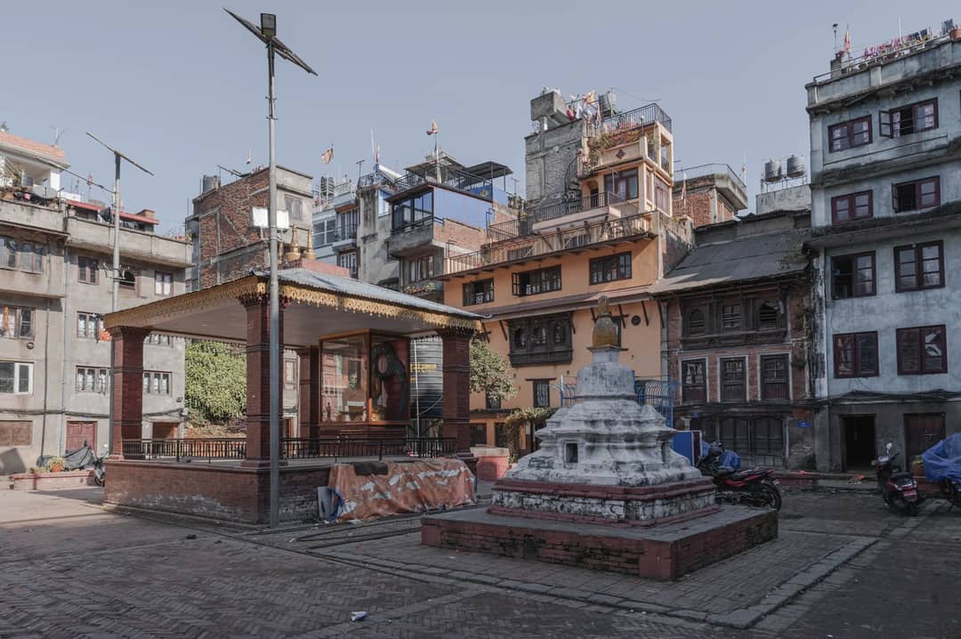 Quaint square in Kathmandu featuring a stupa and traditional Nepali architecture.