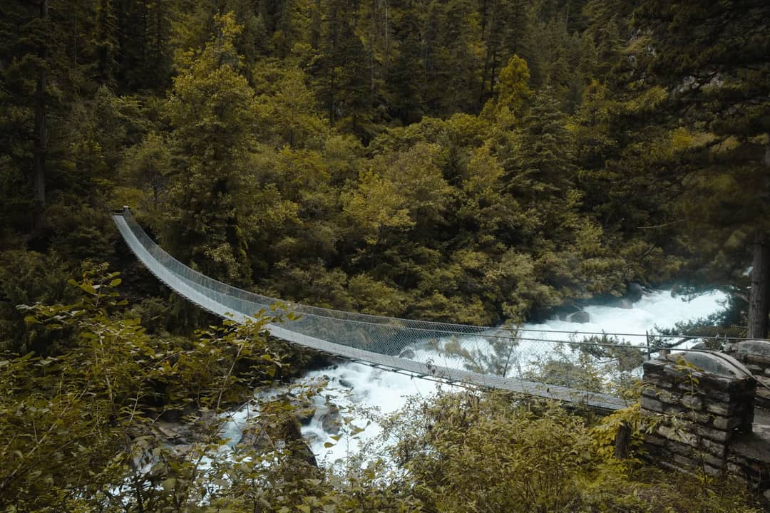 A suspension bridge over a fast white-water river in forest