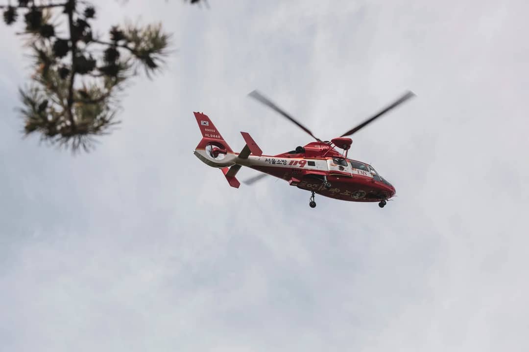 Red and white rescue helicopter flying in the sky, captured outdoors.