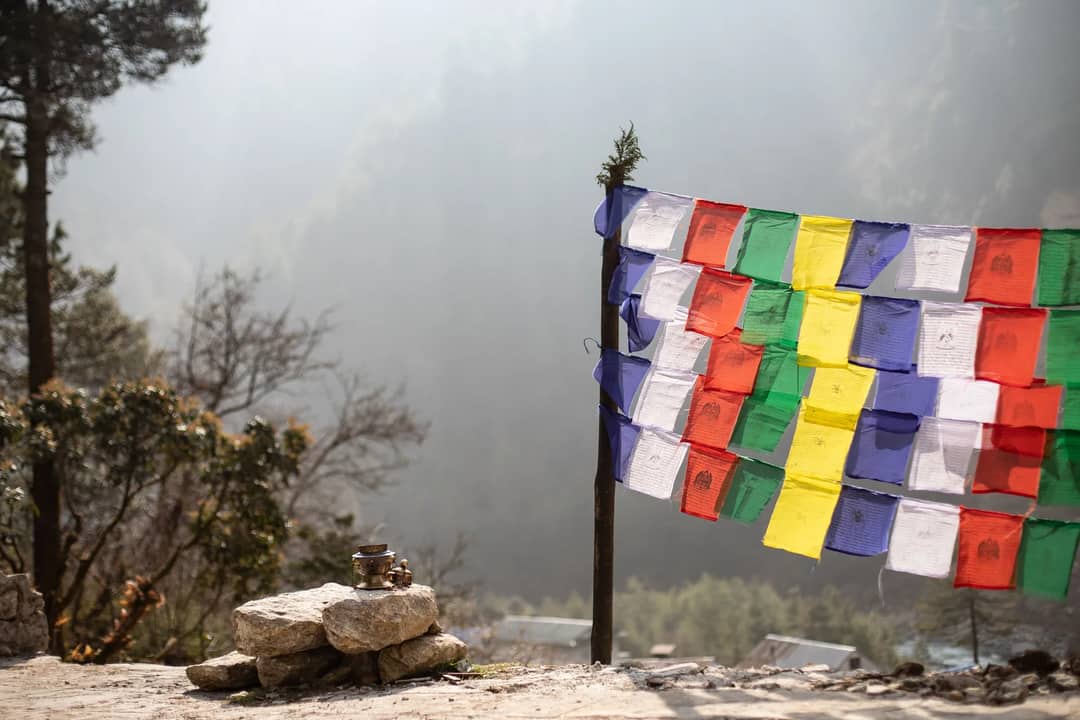 Prayer flags in mist beside a Nepali trail