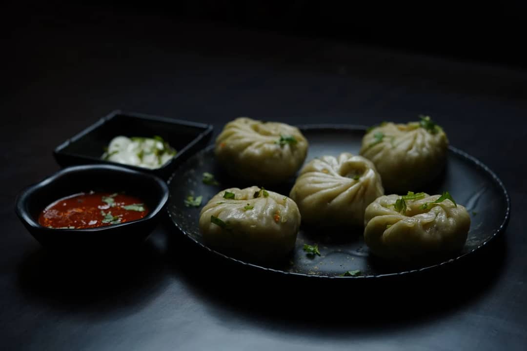 A close-up of Tibetan momos served with spicy and creamy sauces.