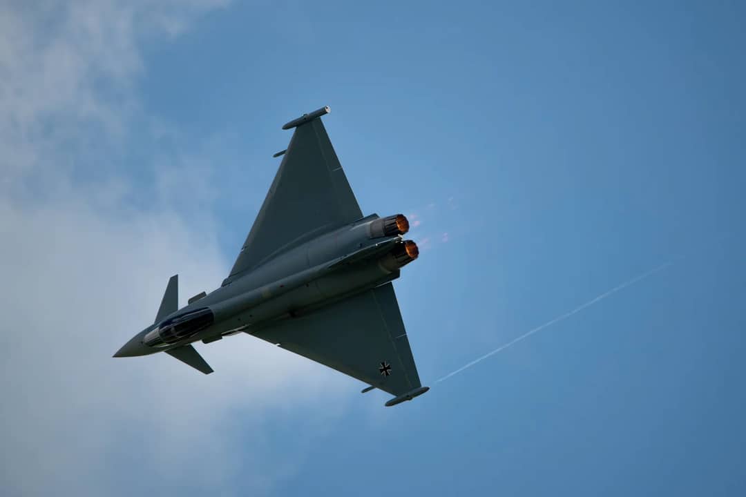 Dynamic shot of a Eurofighter Typhoon jet flying with afterburners on during daytime.