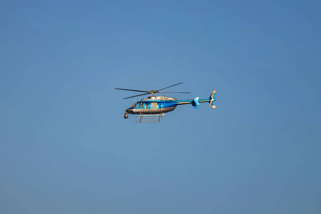 A blue helicopter in flight against a clear blue sky, showcasing smooth aerial maneuvering.