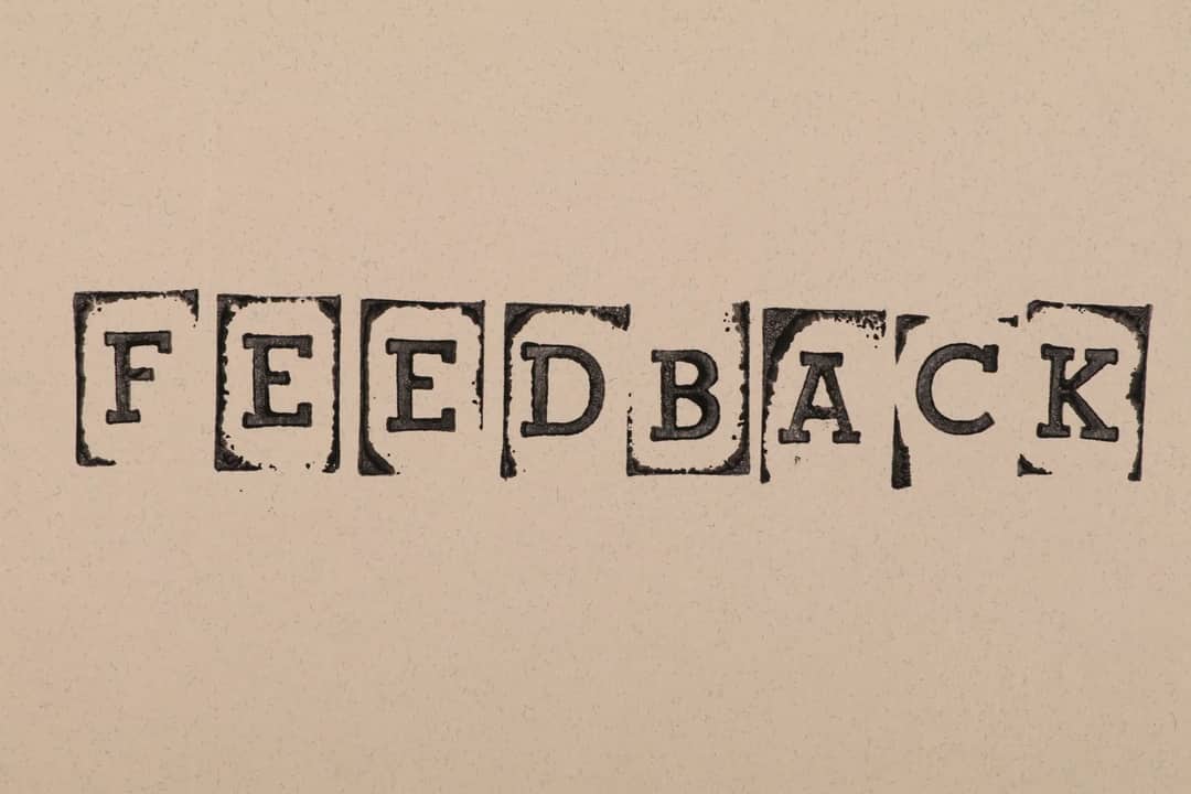 Vintage-style stamped letters spelling 'Feedback' on textured paper background.