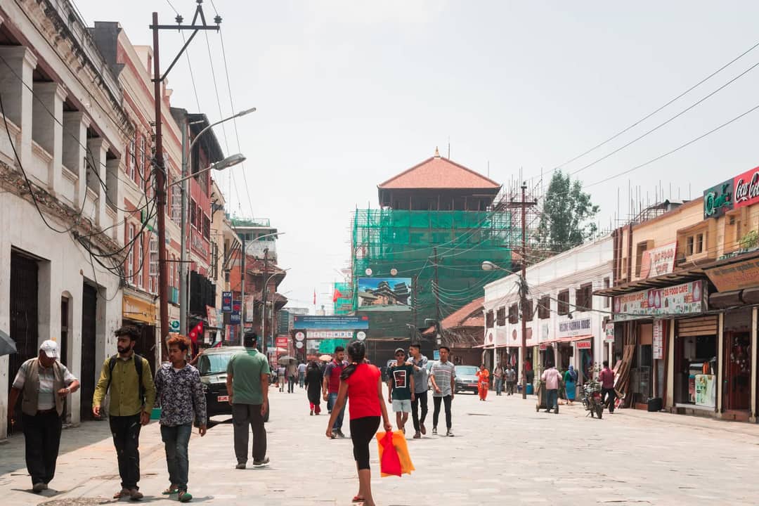 Vibrant street life in Kathmandu with locals and shops on a sunny day.