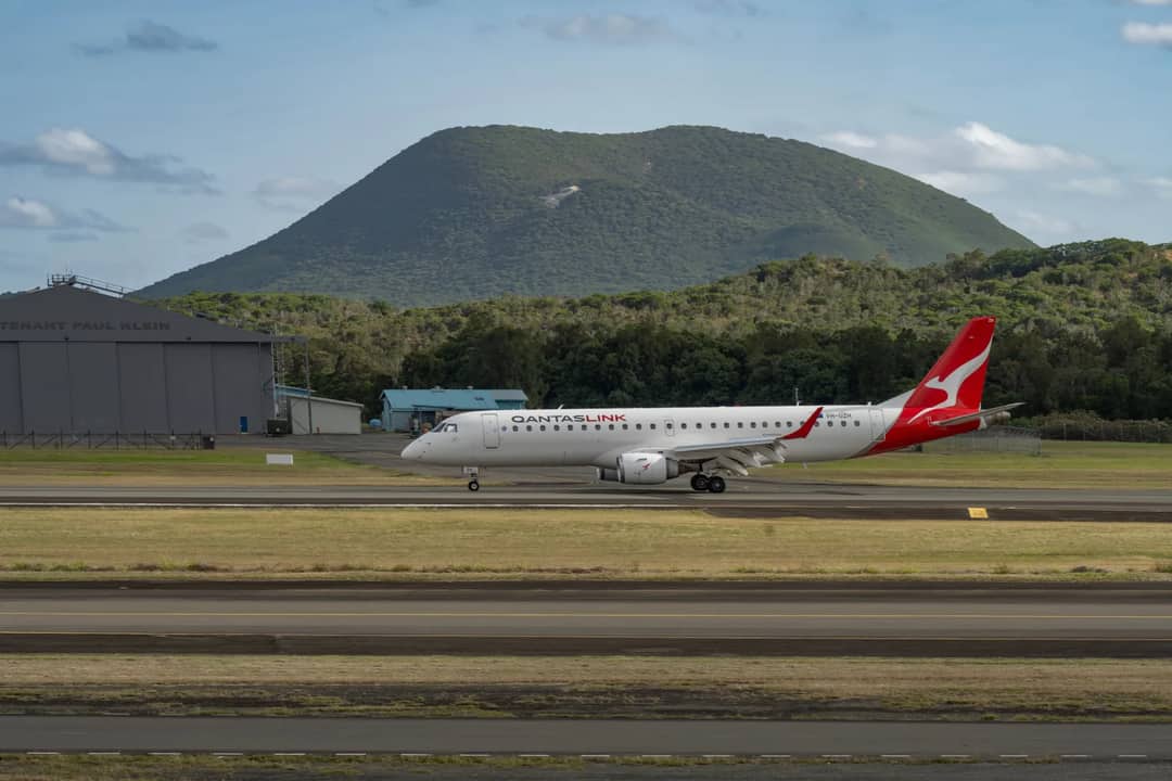 QantasLink aircraft on tarmac with scenic mountain backdrop ready for takeoff.