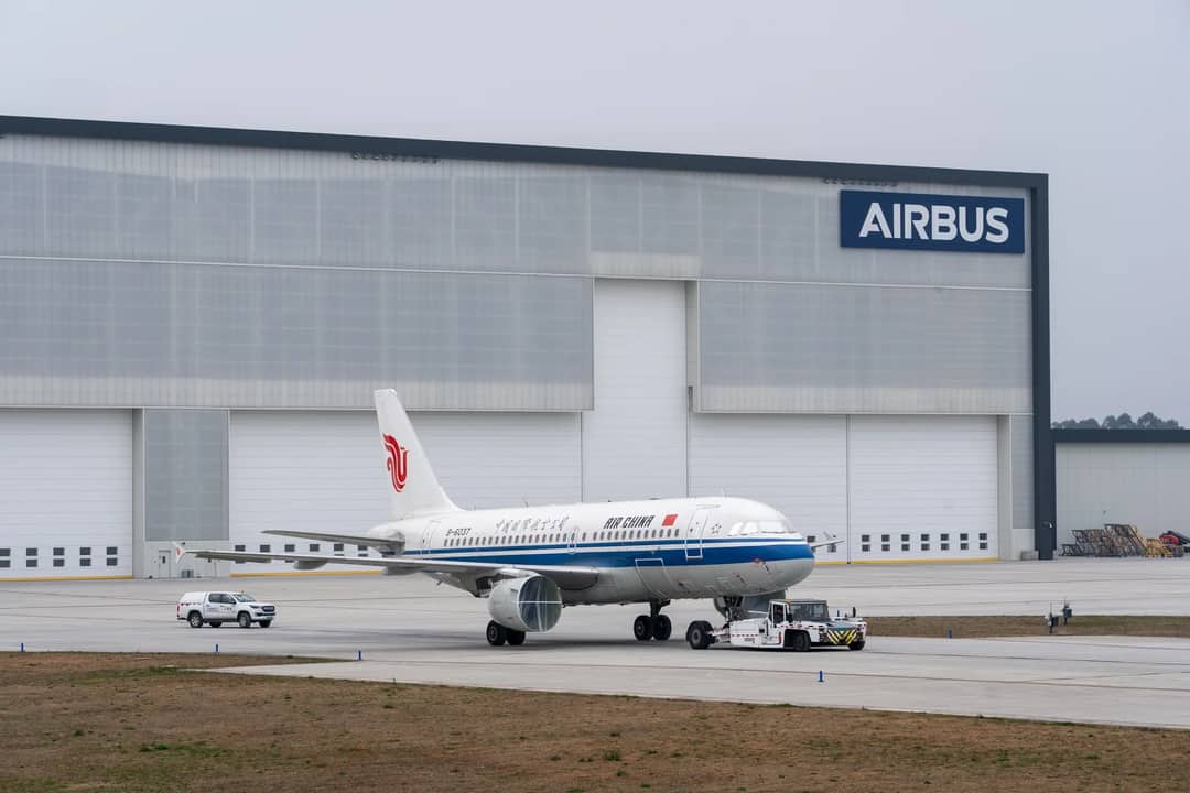 Air China aircraft being towed in front of Airbus hangar.