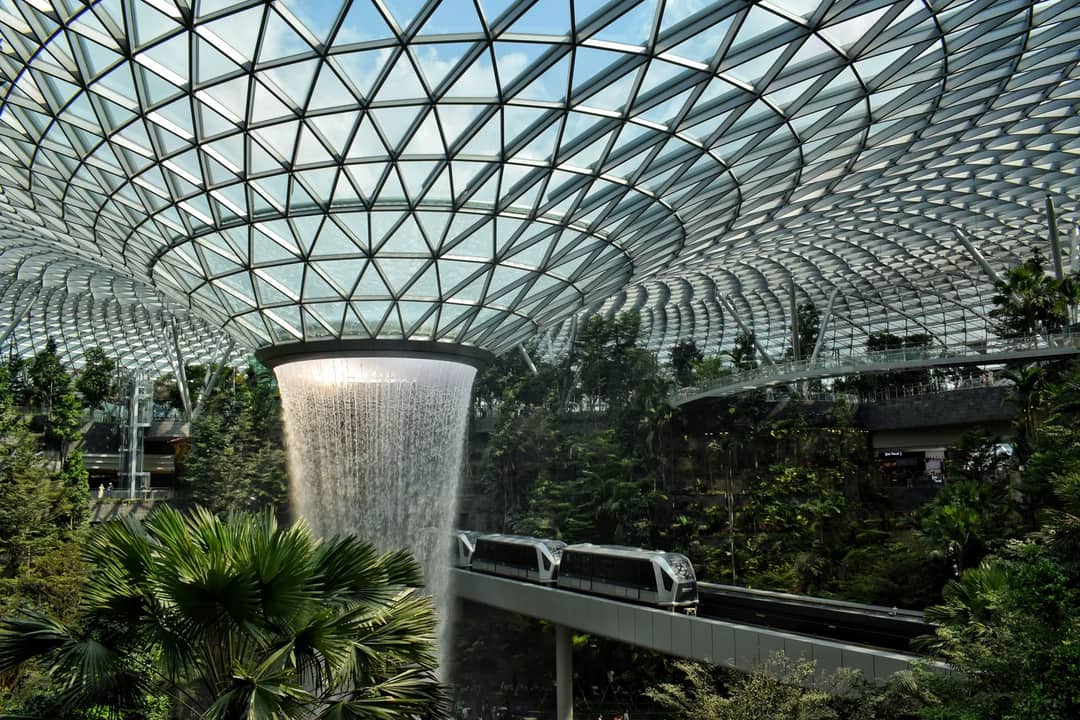 Modern indoor waterfall at Jewel Changi Airport, showcasing lush greenery and cutting-edge architecture.