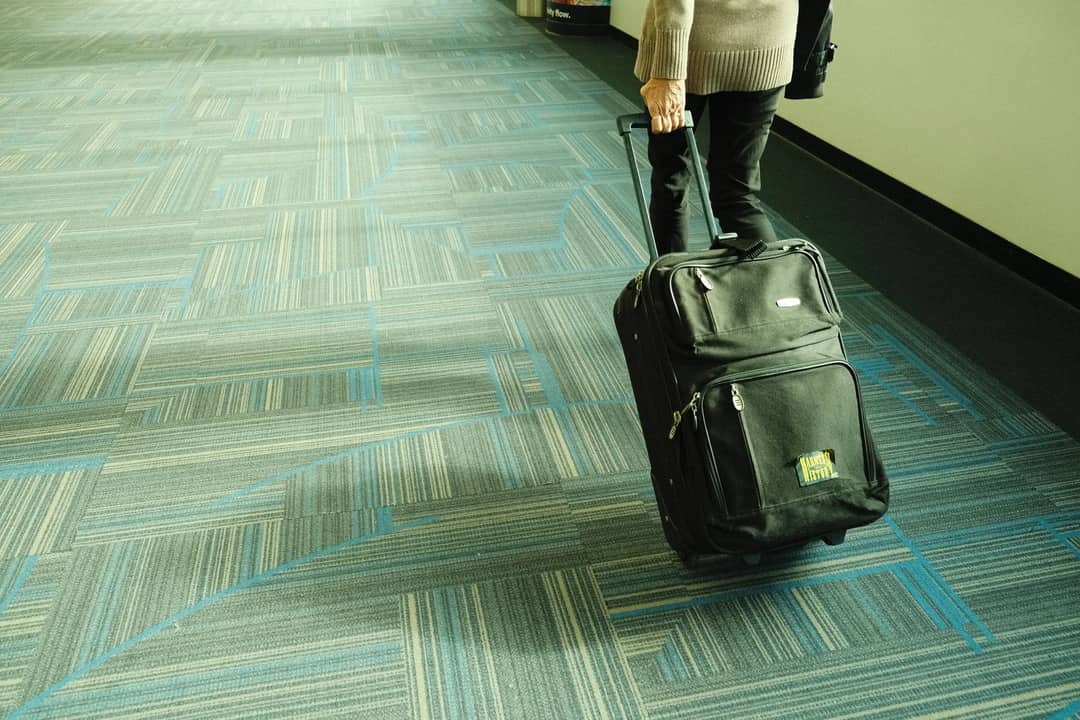 A traveller walking through an airport terminal with a suitcase
