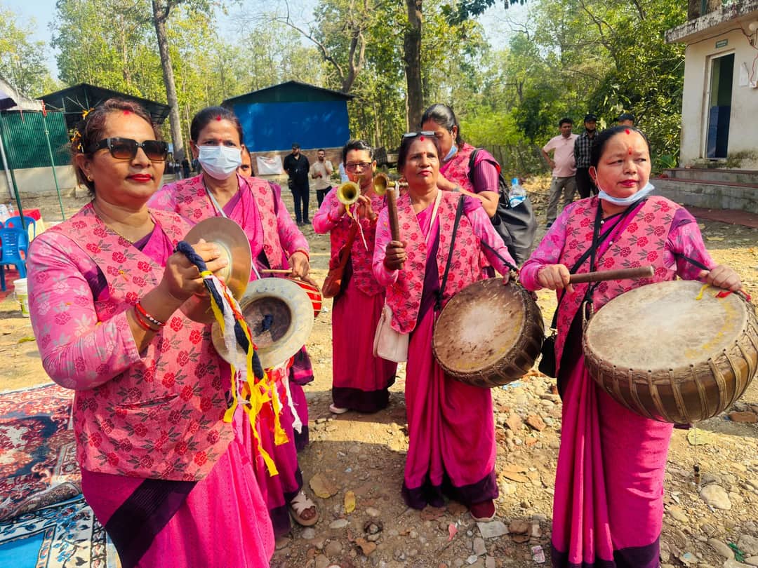 Group of Nepali women in traditional attire playing musical instruments outdoors during a cultural event.