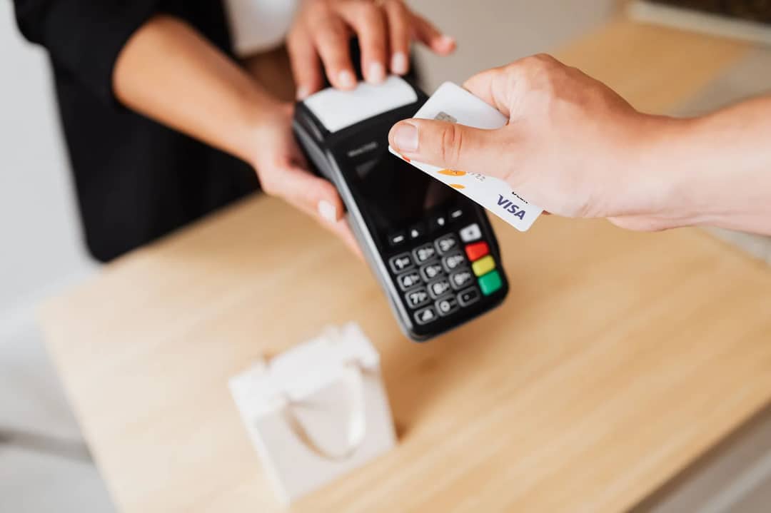 A hand tapping a contactless bank card on a card payment terminal