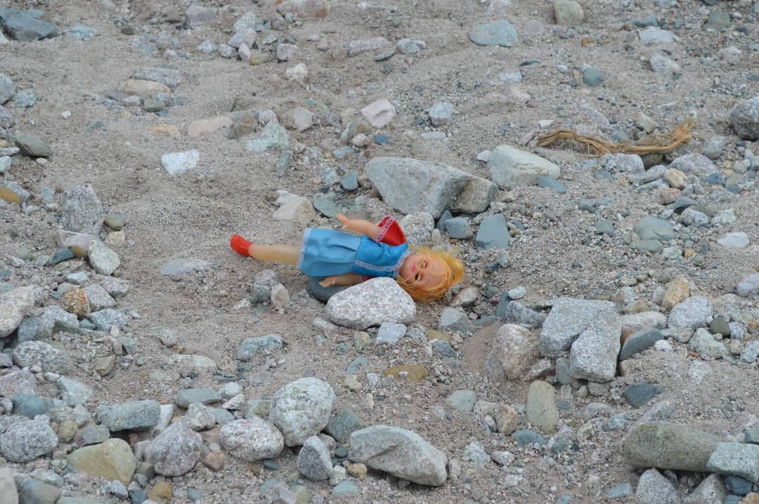 A worn-out doll lies abandoned on rocky terrain in Mocoa, Colombia.