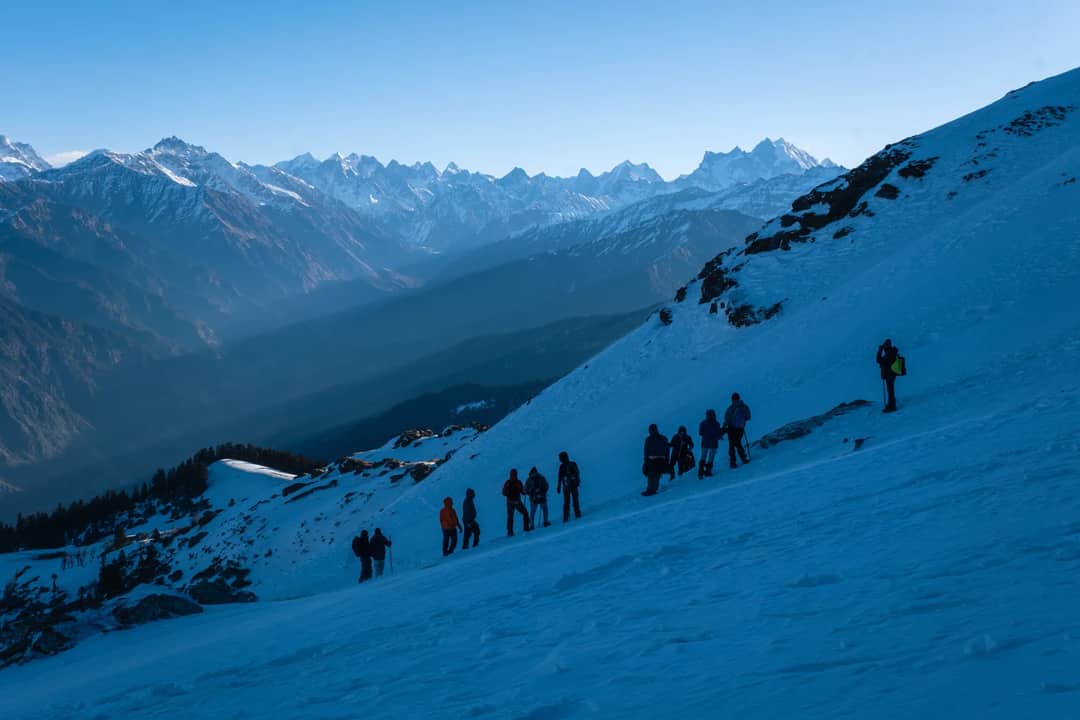Group of trekkers navigating snowy slopes in the majestic Singtur Range, India.