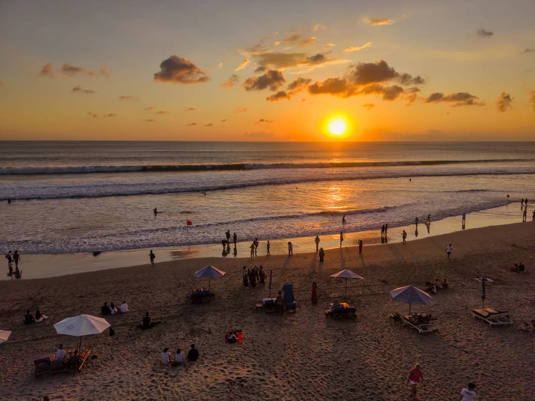 People enjoying a vibrant sunset at Kuta Beach, Bali. Perfect for travel and leisure themes.