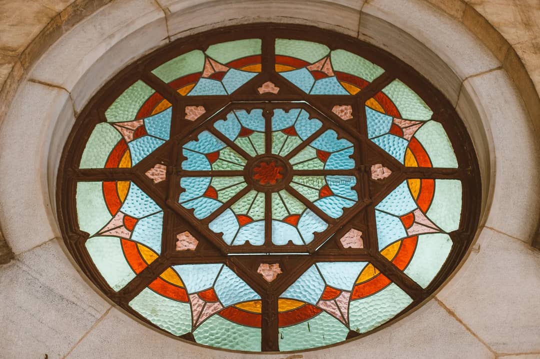 Intricate circular stained glass window featuring vibrant geometric patterns and vivid colors.