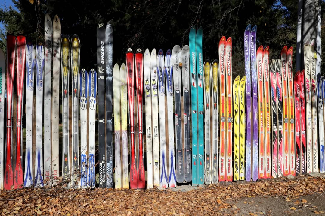 A vibrant collection of varied ski designs arranged outdoors in New Zealand.