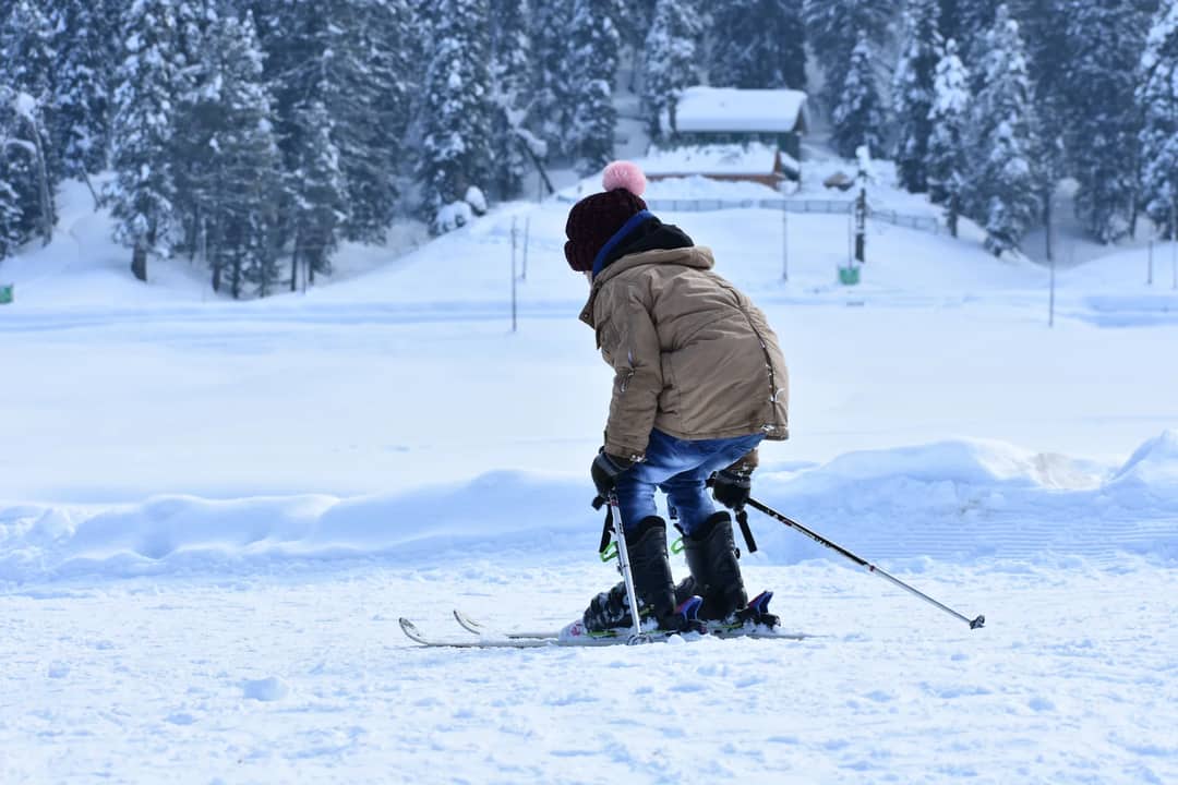 A child in a brown jacket skiing in a snowy landscape, capturing the essence of winter sports fun.