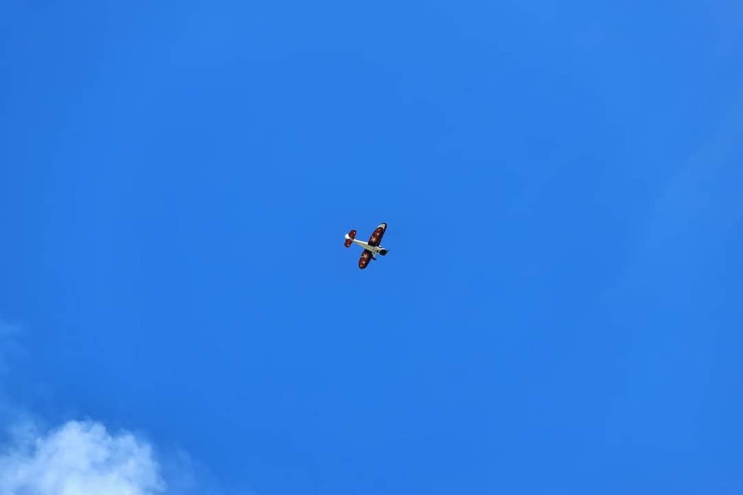 A small airplane flying in a clear blue sky, showcasing an exhibition flight.