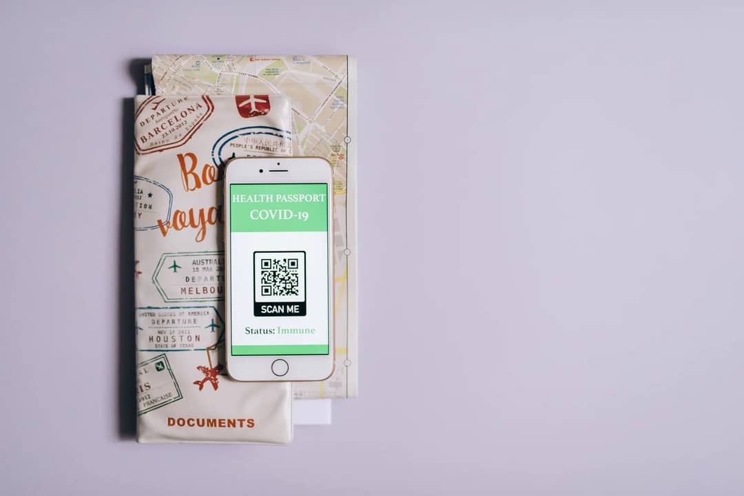 A phone showing a QR code beside a travel document wallet