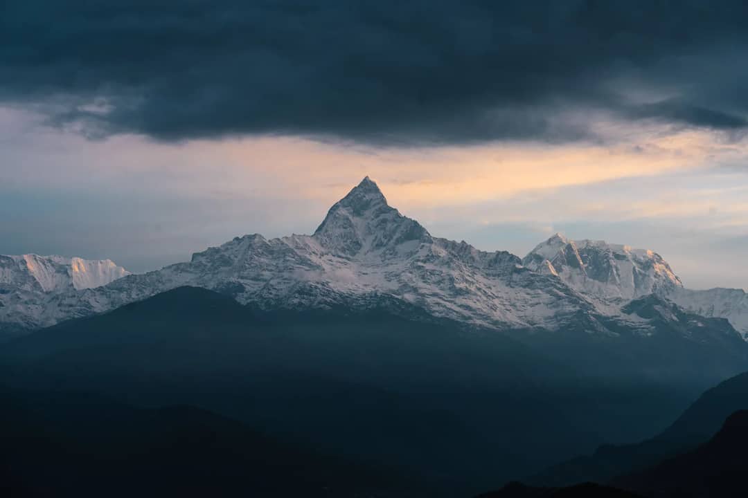 Breathtaking view of the Himalayas with snow-covered peaks under a dramatic twilight sky.