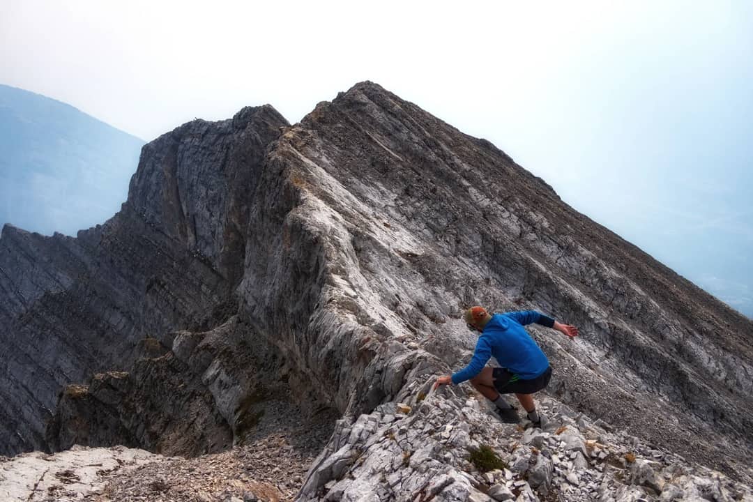 Dynamic shot of a man climbing a rugged mountain ridge in Alberta, Canada. Perfect for adventure and nature themes.