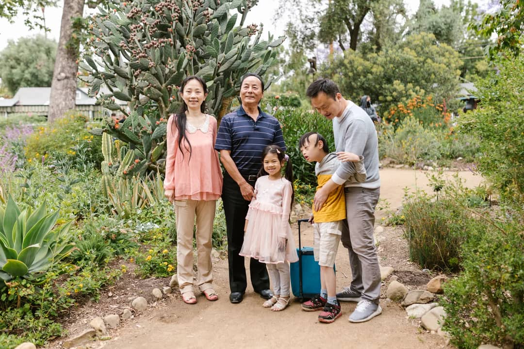 A joyful Asian family enjoys a day outdoors in a lush garden, promoting inclusion and togetherness.