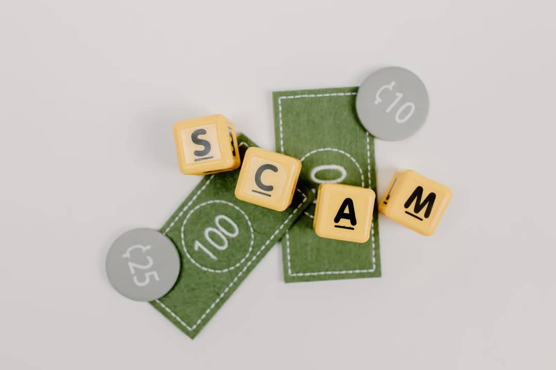 Yellow dice spelling 'Scam' on fake currency, representing financial deception.