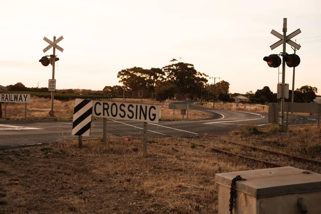 Quiet rural railway crossing at sunset with crossing signs and empty tracks.