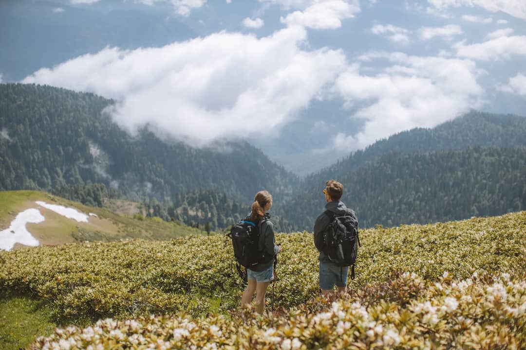 Couple hiking through lush mountain landscape. Scenic adventure travel.