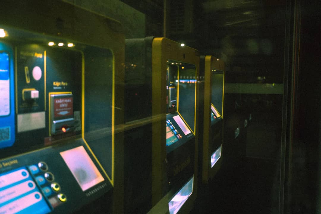 Row of illuminated ticket machines in a dark setting with a reflective perspective.