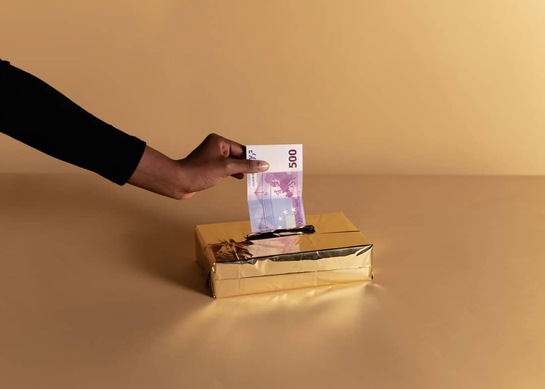 Euro banknote held by a hand against beige background, symbolizing bribery or gifting.