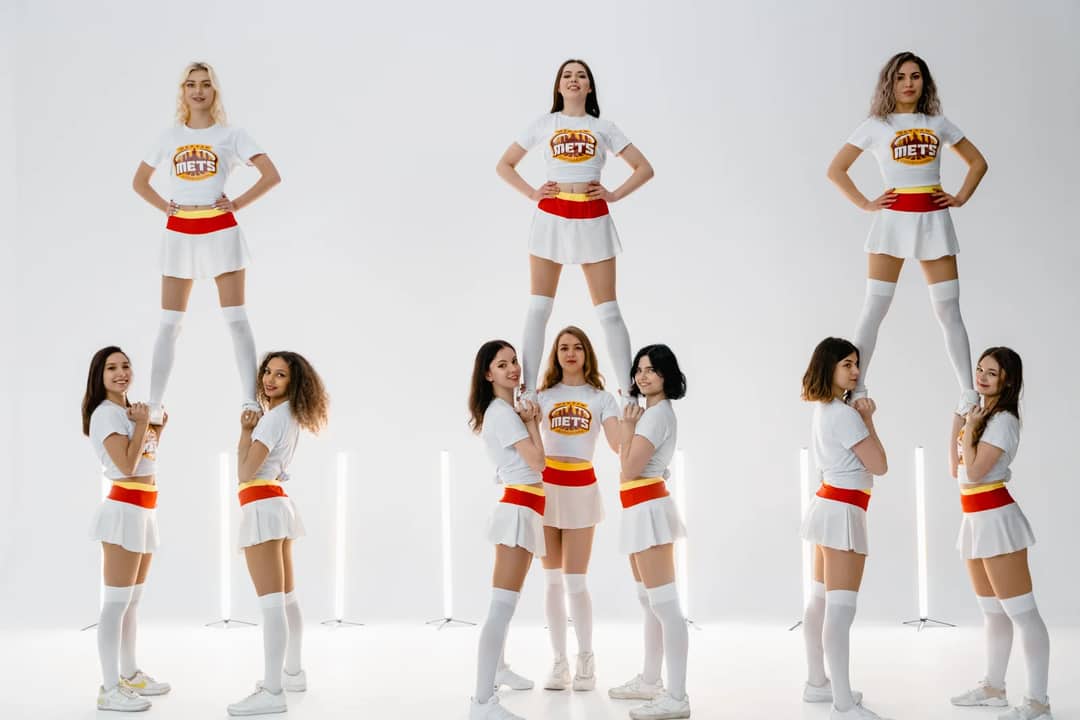 Group of cheerleaders performing stunts in a studio, showcasing energy and teamwork.