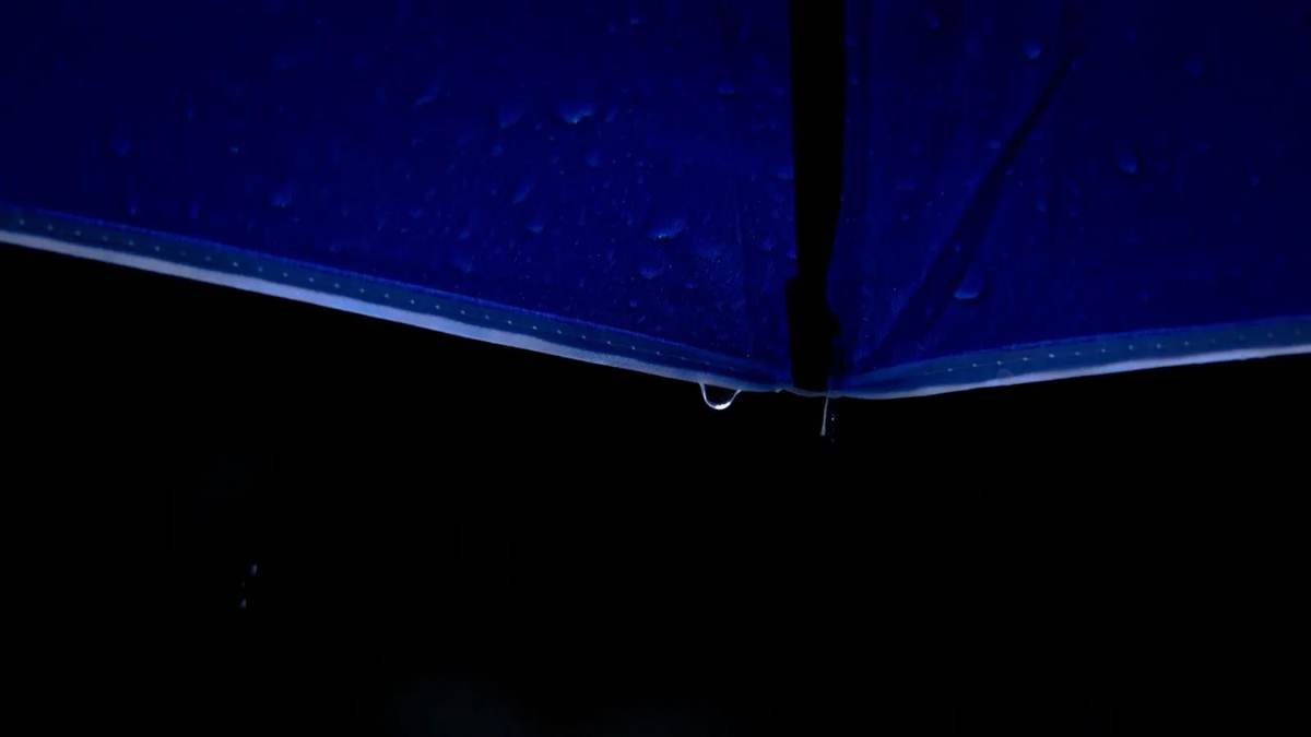 Rain beading on the shoulder of a waterproof shell — water repellency is a surface finish that wears off long before the membrane underneath fails