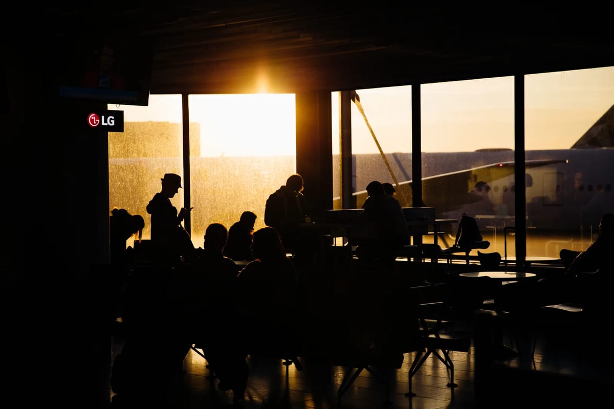 Travellers sitting in an airport terminal at sunset