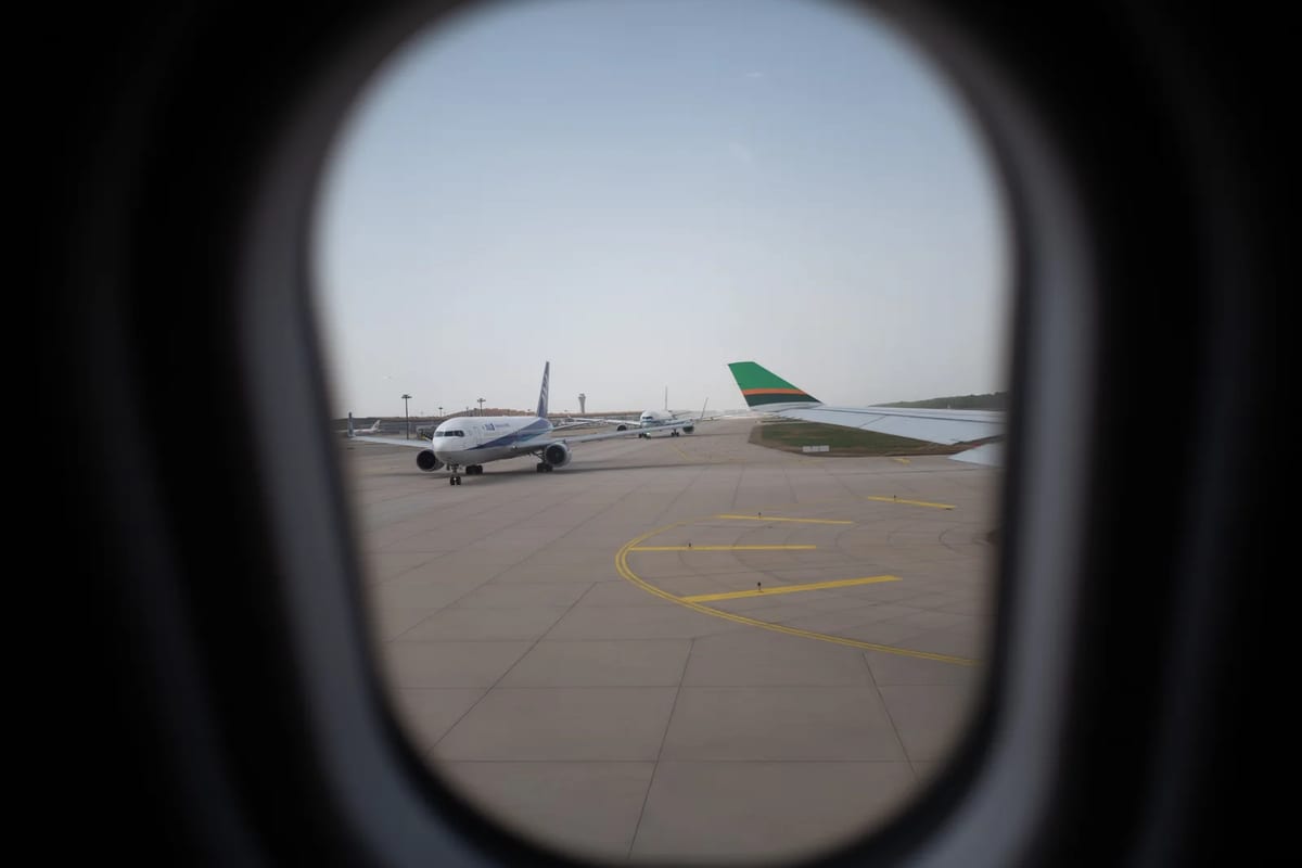 An airplane parked on an airport apron, seen through a terminal window