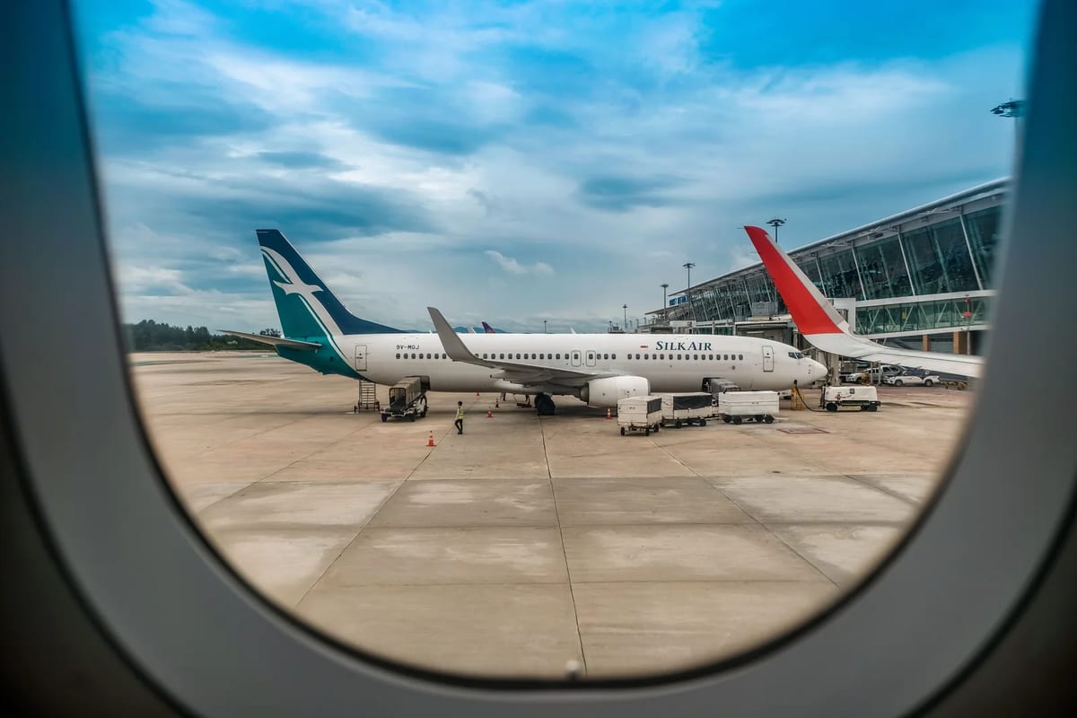 Airplanes on a tarmac seen from an airplane window under a blue sky
