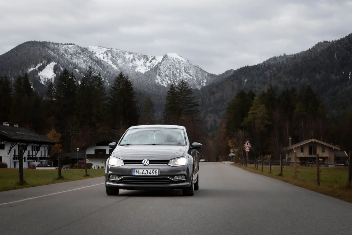 A car on a road near Tegernsee in Germany with snowy mountains behind