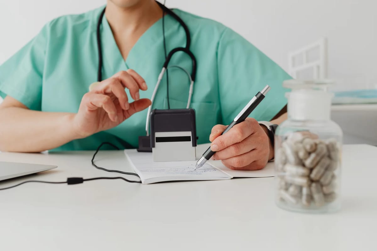 A doctor writing a prescription at a clinic desk