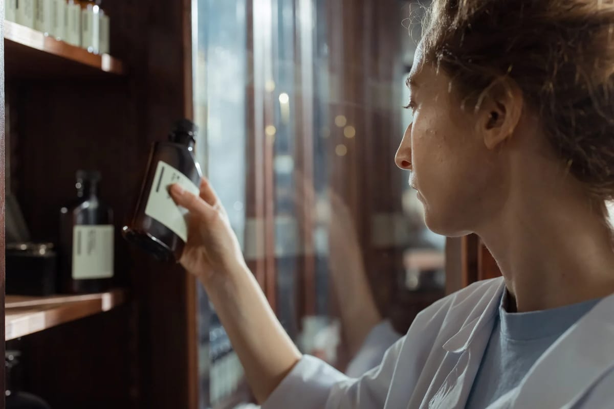 A pharmacist taking a medicine bottle from a pharmacy shelf