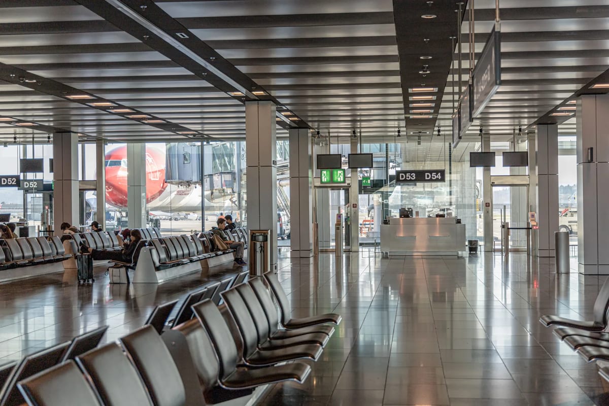 An airport transit area with seating and an aircraft outside the window
